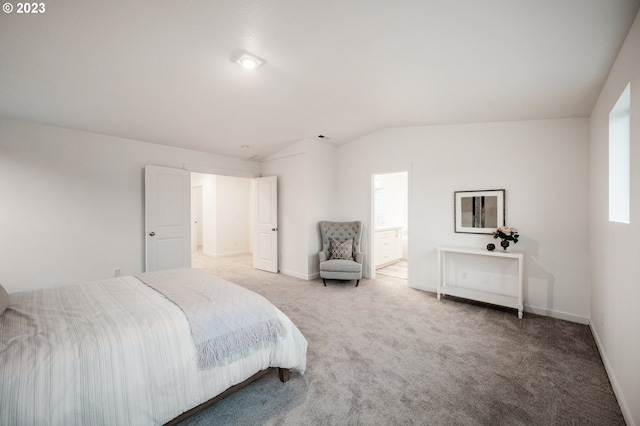 bedroom featuring carpet floors, ensuite bathroom, and vaulted ceiling