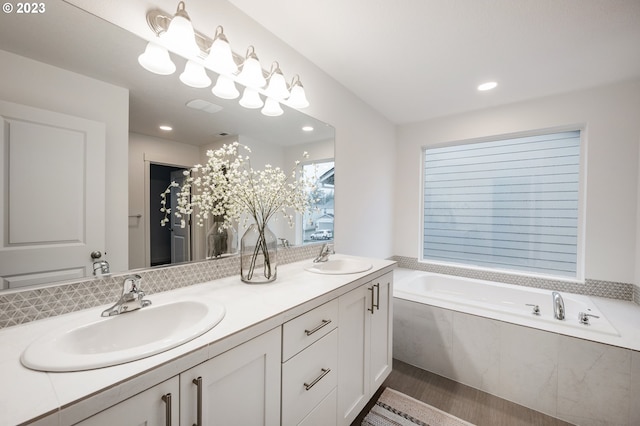 bathroom featuring hardwood / wood-style flooring, vanity, and tiled bath