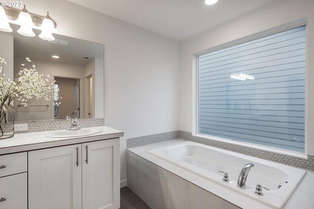 bathroom with vanity and a relaxing tiled tub