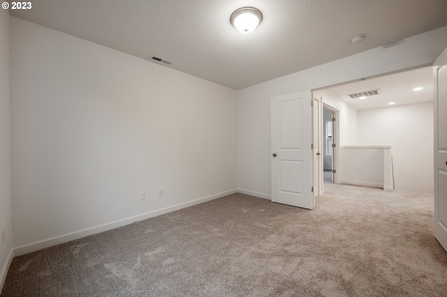 carpeted empty room featuring a textured ceiling