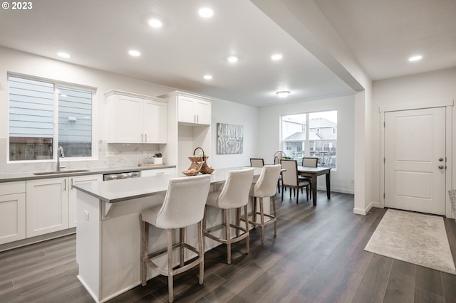 kitchen featuring white cabinetry, a center island, sink, dark hardwood / wood-style floors, and a kitchen bar