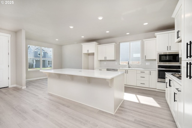 3104 S Kodiak St Unit Lt814, Cornelius, OR 97113 - kitchen featuring oven, black microwave, a center island, tasteful backsplash, and white cabinetry