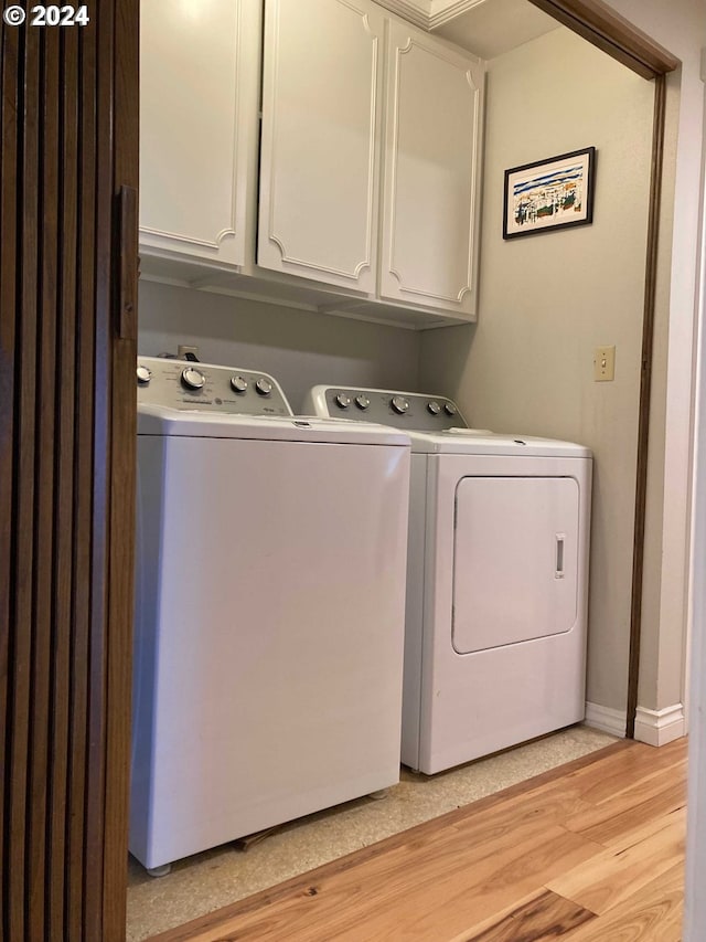 laundry area featuring light wood-type flooring, cabinets, and washer and clothes dryer