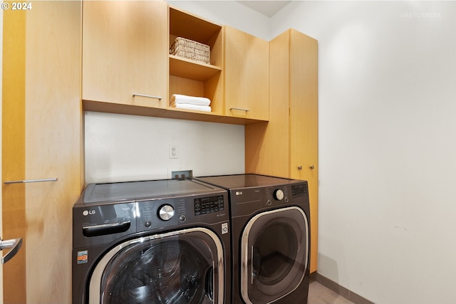 clothes washing area with cabinets and washer and clothes dryer