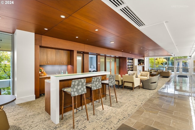 kitchen featuring a wealth of natural light, sink, wooden ceiling, and a breakfast bar area