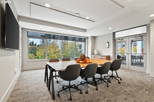 carpeted dining room featuring french doors and a tray ceiling