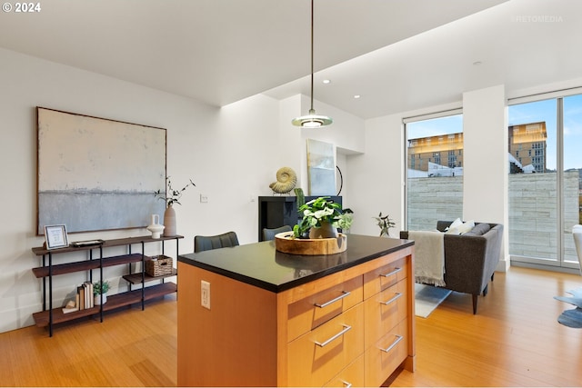 kitchen with pendant lighting, a wall of windows, light hardwood / wood-style flooring, and a kitchen island