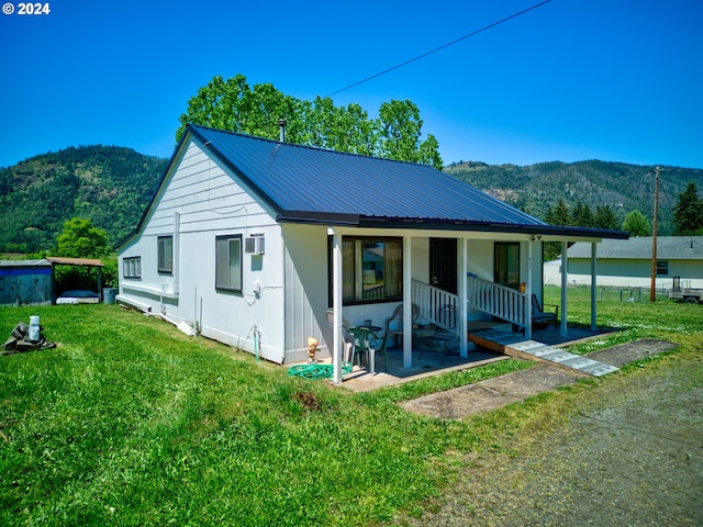 view of front of home featuring a front yard, a mountain view, and covered porch