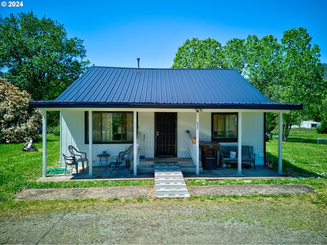 bungalow-style home with a front yard, covered porch, and metal roof