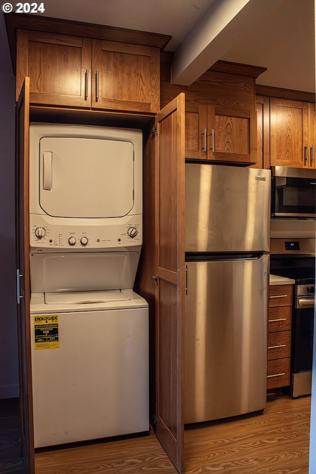 clothes washing area with stacked washing maching and dryer and light hardwood / wood-style floors