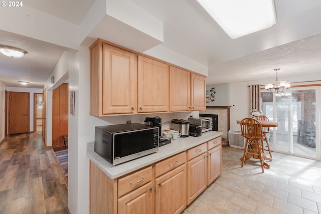 kitchen with light brown cabinetry, an inviting chandelier, light hardwood / wood-style flooring, and a textured ceiling