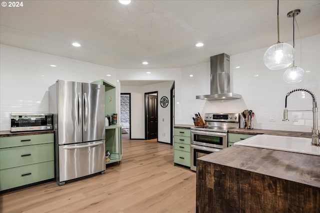 kitchen with appliances with stainless steel finishes, wall chimney exhaust hood, and green cabinets