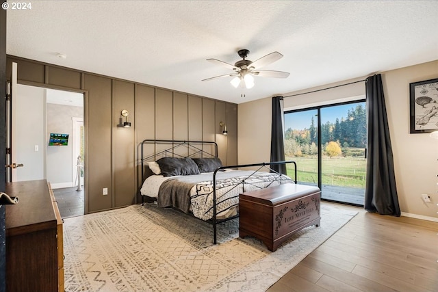 bedroom featuring ceiling fan, light hardwood / wood-style flooring, access to exterior, and a textured ceiling