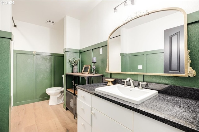 bathroom with hardwood / wood-style floors, toilet, and vanity