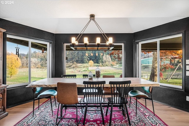 dining space featuring a chandelier, light hardwood / wood-style flooring, and vaulted ceiling