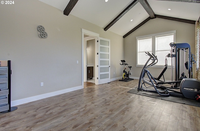 exercise room featuring light wood-type flooring and vaulted ceiling