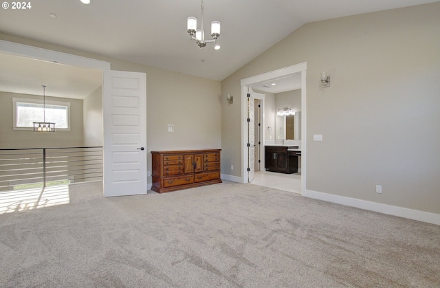 spare room featuring light colored carpet, vaulted ceiling, and a notable chandelier