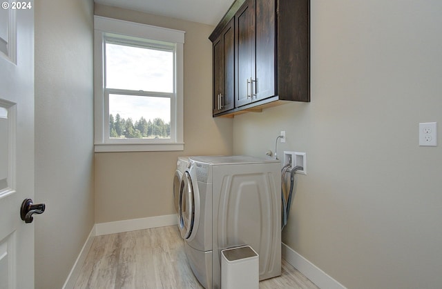 laundry area with cabinets, independent washer and dryer, and light wood-type flooring