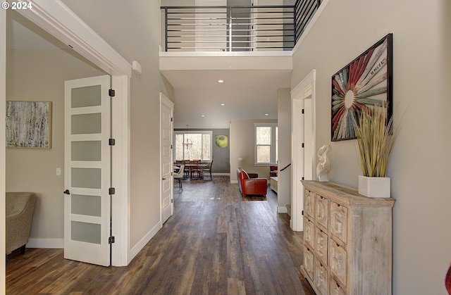 corridor with dark hardwood / wood-style flooring and a towering ceiling