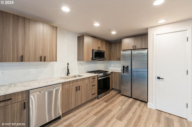 kitchen featuring light wood-type flooring, sink, appliances with stainless steel finishes, and tasteful backsplash