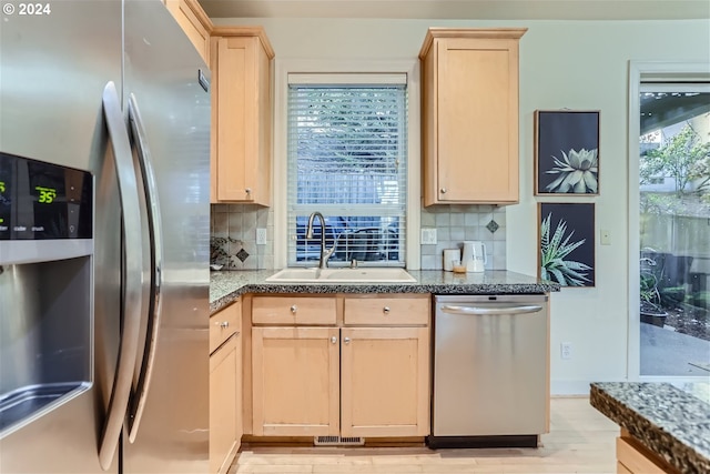 kitchen featuring backsplash, sink, light brown cabinetry, light hardwood / wood-style floors, and stainless steel appliances