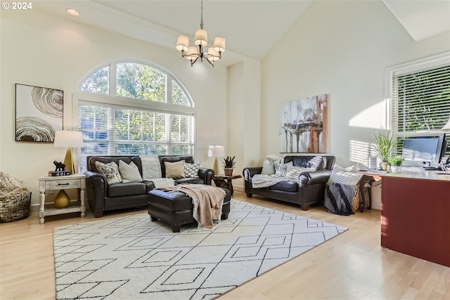 sitting room with a notable chandelier, light wood-type flooring, and high vaulted ceiling