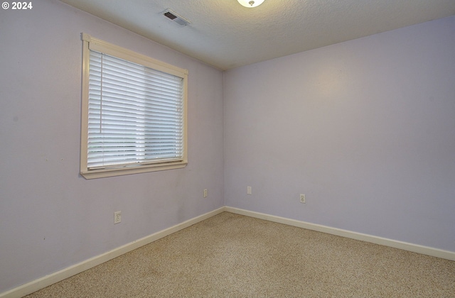 carpeted empty room with a textured ceiling