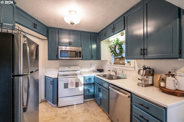 kitchen featuring blue cabinetry, sink, stainless steel appliances, and a textured ceiling