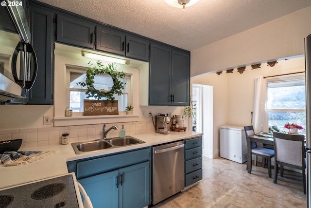 kitchen with tasteful backsplash, sink, stainless steel appliances, and a textured ceiling