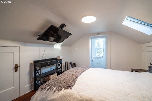 bedroom featuring vaulted ceiling with skylight and dark hardwood / wood-style flooring