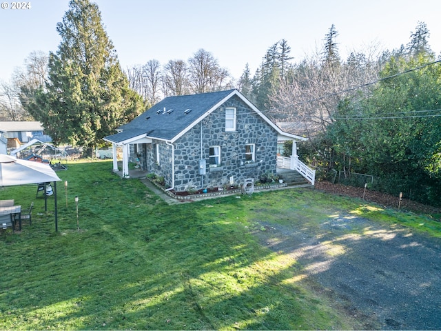 rear view of house featuring a gazebo and a yard