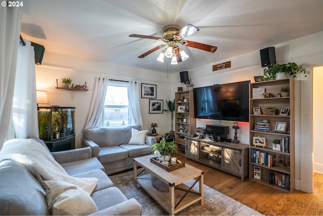 living room featuring wood-type flooring, a textured ceiling, and ceiling fan