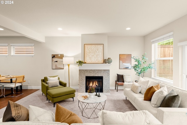 living room featuring beam ceiling, hardwood / wood-style flooring, and a tile fireplace