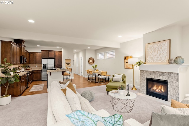 living room with light wood-type flooring and a tile fireplace