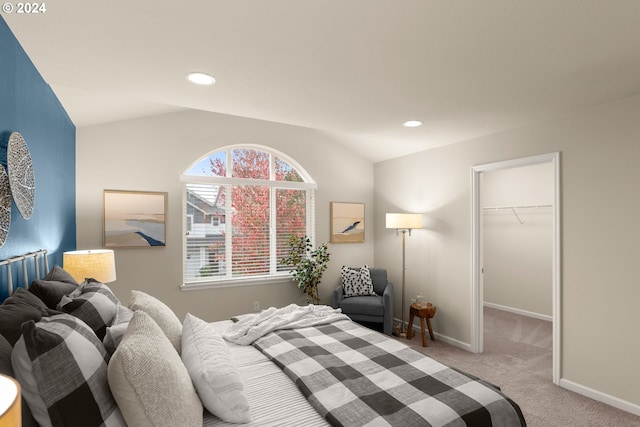 carpeted bedroom with a spacious closet, a closet, and vaulted ceiling