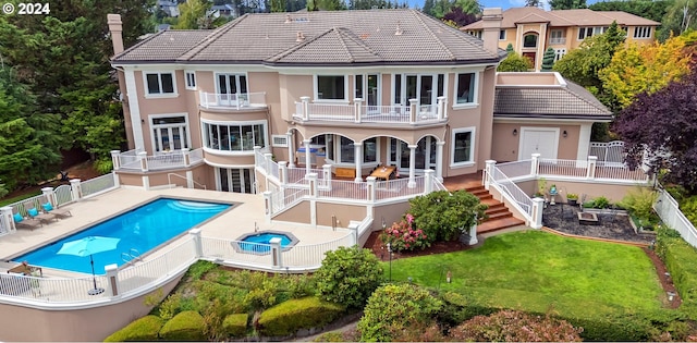 back of house with a lawn, a balcony, and a fenced in pool