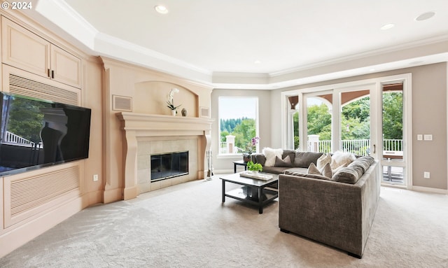 tiled living room with a wealth of natural light, crown molding, a raised ceiling, and a tile fireplace