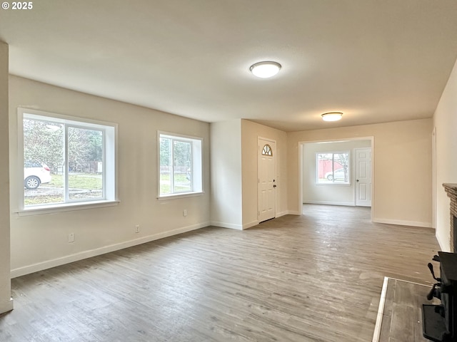 unfurnished living room featuring wood-type flooring and a wood stove