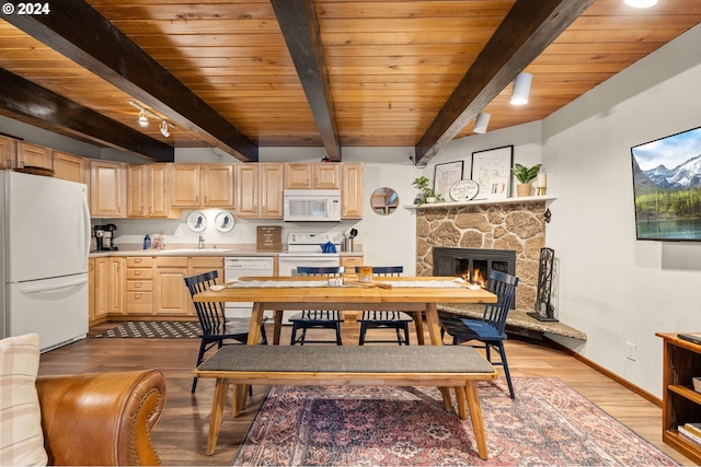 dining room with beamed ceiling, rail lighting, a fireplace, and wood ceiling