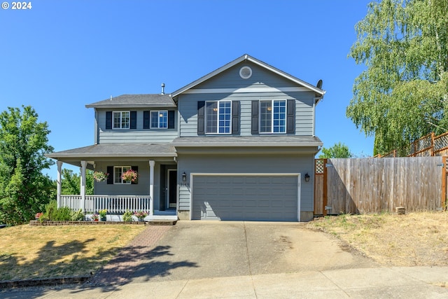 view of front of home with a garage, concrete driveway, a porch, and fence