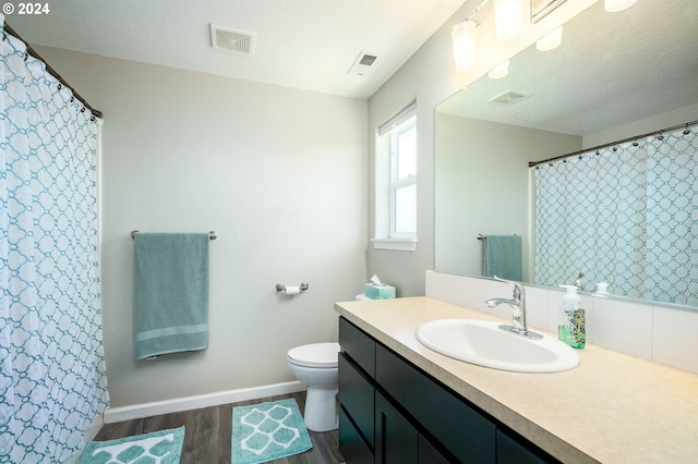 full bath with toilet, visible vents, wood finished floors, and vanity