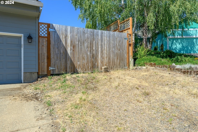 view of yard featuring a garage, a gate, and fence