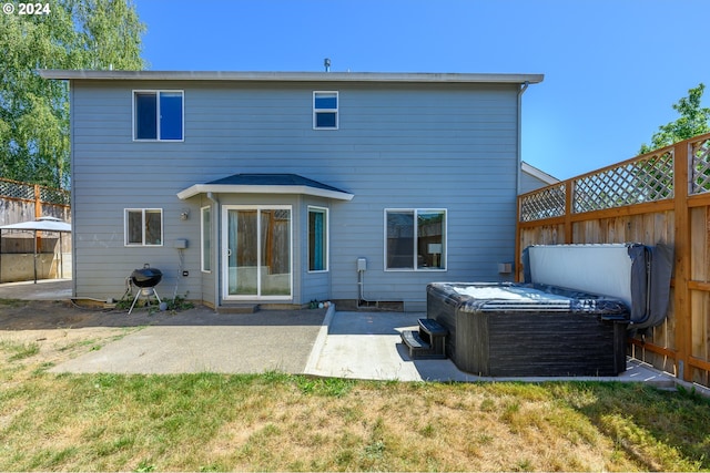 back of house featuring a yard, a patio area, a fenced backyard, and a hot tub