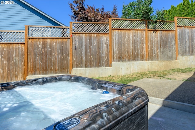 view of patio with a hot tub and fence