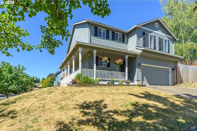 view of front of home with concrete driveway, an attached garage, fence, a porch, and a front yard