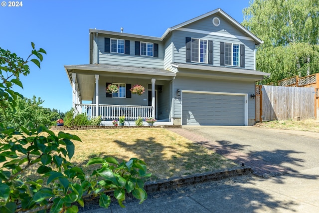 traditional-style home with a porch, concrete driveway, fence, and an attached garage