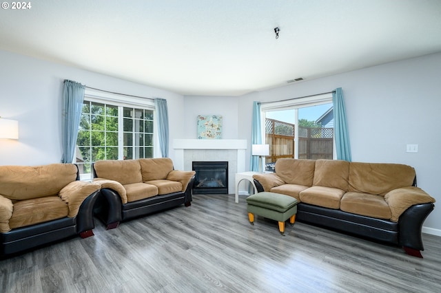 living area with a tiled fireplace, wood finished floors, and visible vents