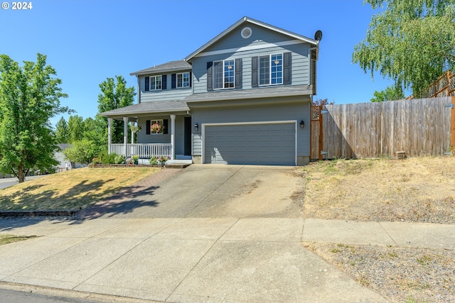 traditional home with covered porch, driveway, fence, and a garage