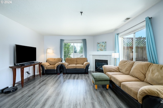 living room with a tile fireplace, wood finished floors, visible vents, and baseboards