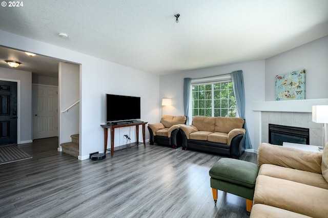 living area with a tile fireplace, stairway, baseboards, and wood finished floors